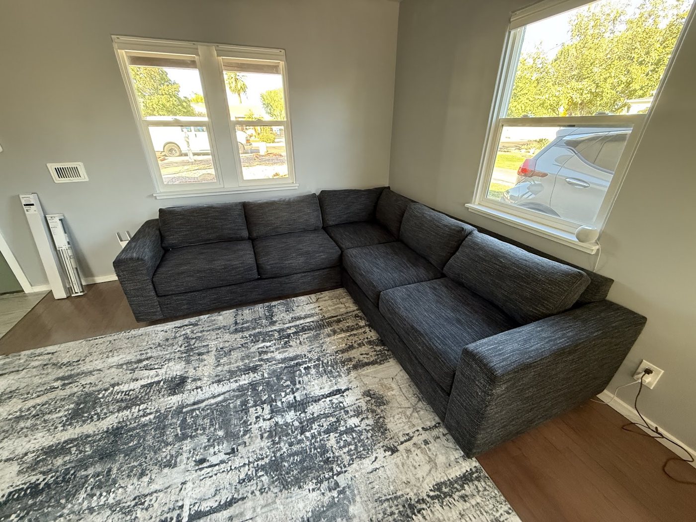 A gray sectional couch on a patterned area rug in a Tempe living room